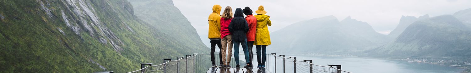 Norway, Senja island, rear view of friends standing on an observation deck at the coast