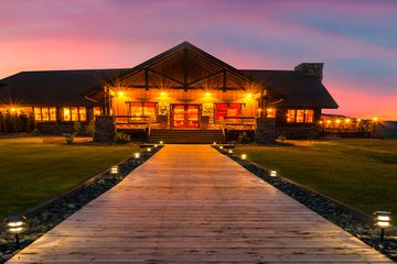 Wooden path through grass leading to lodge at dusk