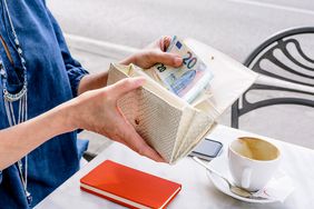 Hand of mature woman removing euro note from purse at sidewalk cafe, Fiesole, Tuscany, Italy