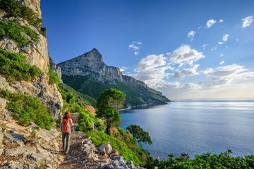 A woman hiking on a trail on the Sardinian coast