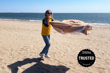 tout: person shaking out a turkish beach towel at the beach