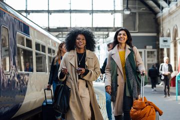 Two friends traveling a train station platform in England