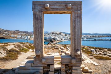 View through the famous Portara marble gate of Naxos island to the city and harbour, Cyclades, Greece