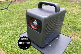 Anker Nebula Cosmos Laser 4K Projector displayed on a small outdoor table
