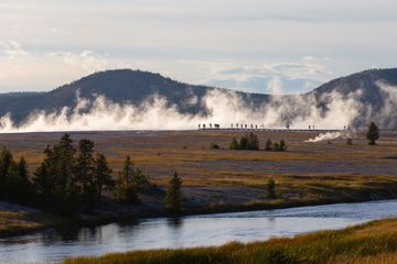 People on a walkway observing a geyser